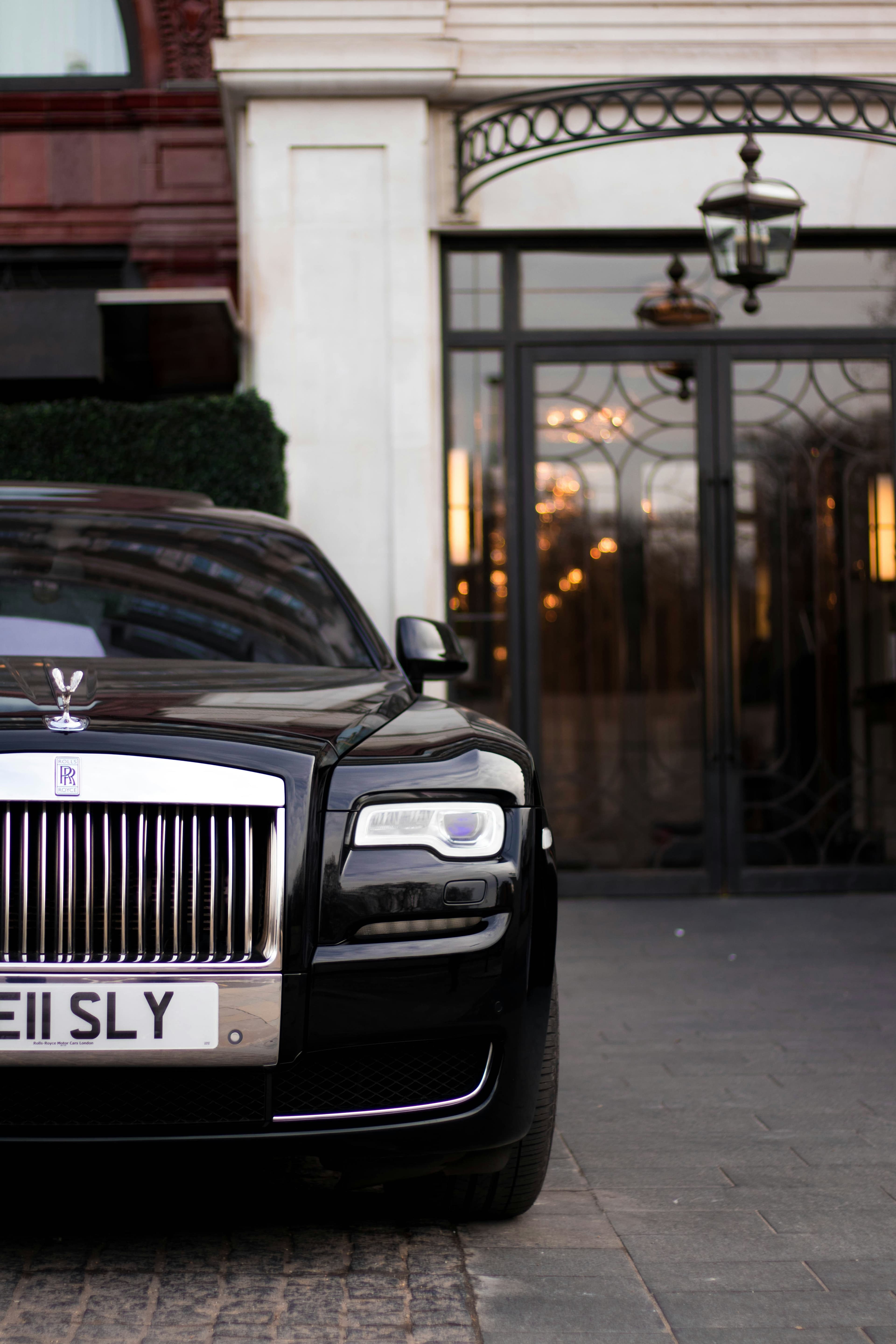 A front view of a rolls royce parked outside of a smart building.