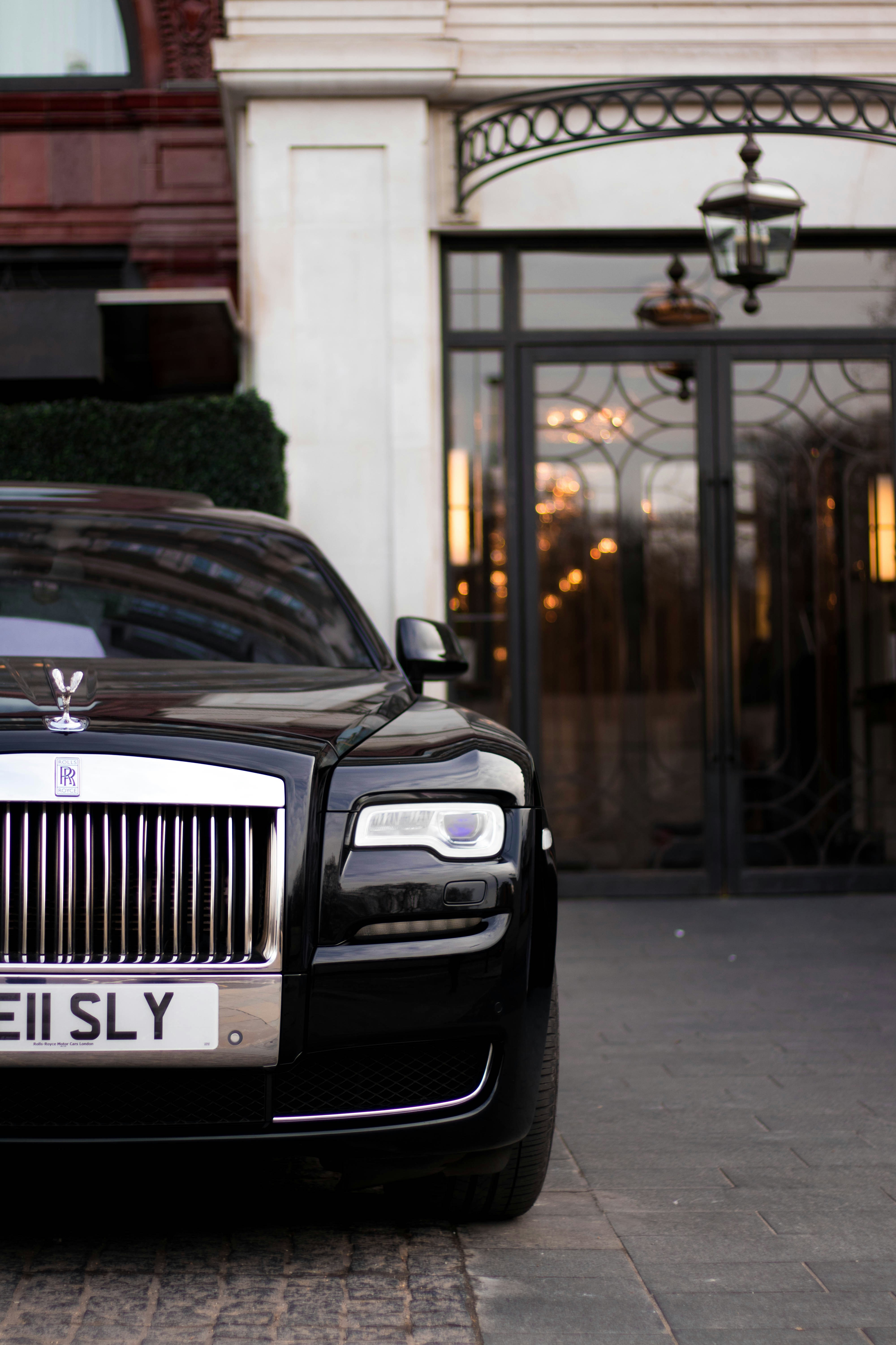 A front view of a rolls royce parked outside of a smart building.