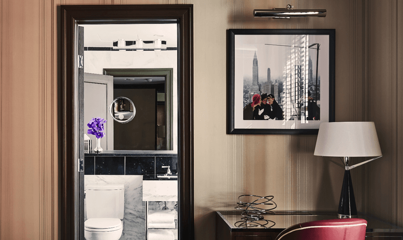 A view of a desk area and bathroom at Hotel Iroquois, New York.