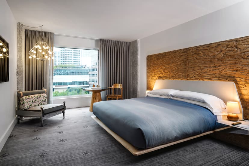 A modern hotel room at The LINE Austin with large windows looking out onto a body of water and greenery.