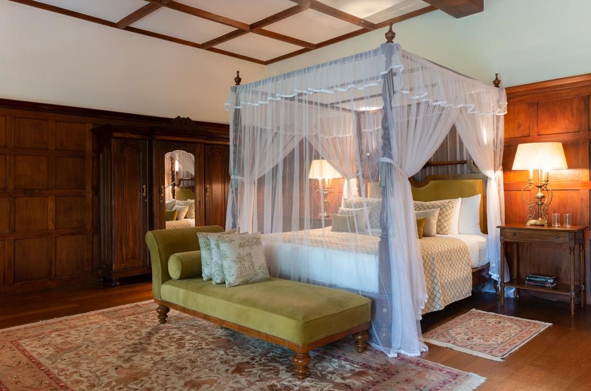 a four-post canopy bed near a green couch