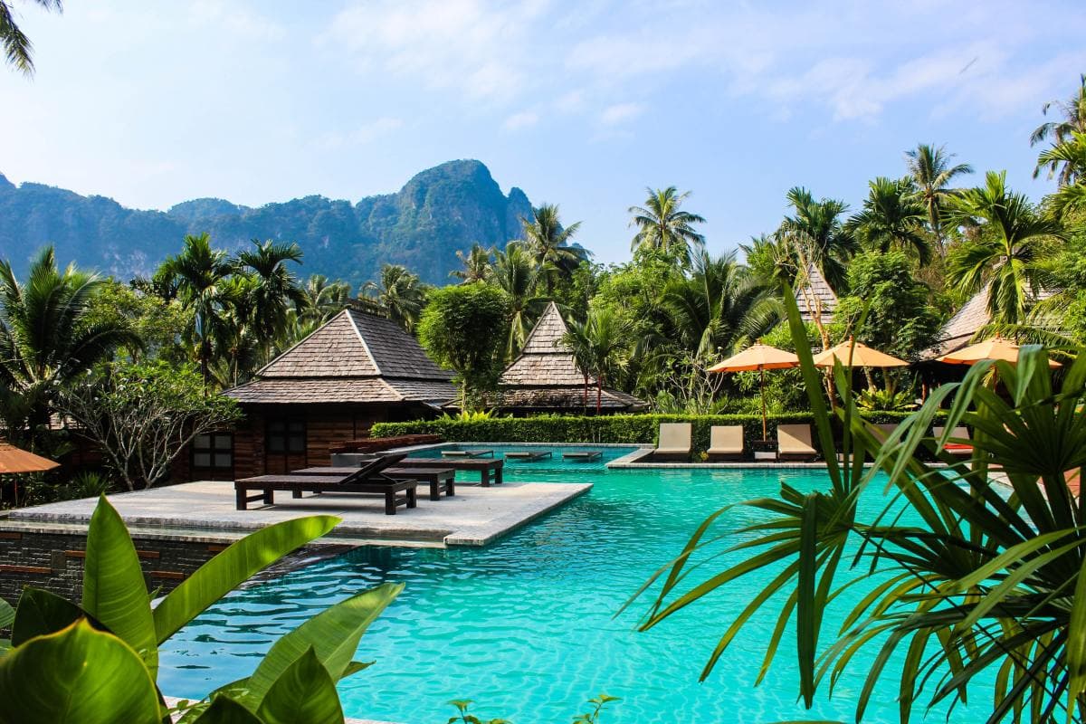bright blue pool surrounded by palm trees and cabanas in Asia