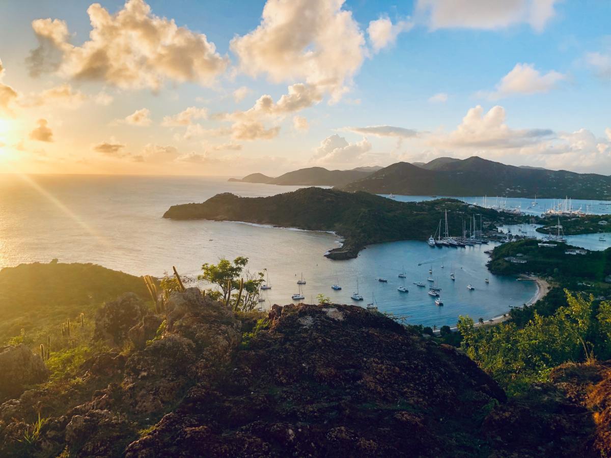 Sun setting over ocean and green islands in Antigua and Barbuda in the Caribbean.