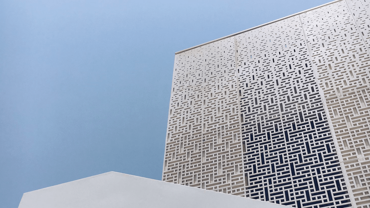 A beautiful, geometric white building in front of a clear blue sky.