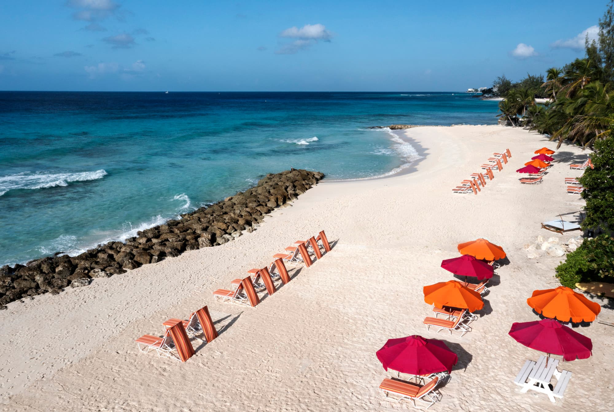 a Caribbean beach dotted with pink and orange umbrellas