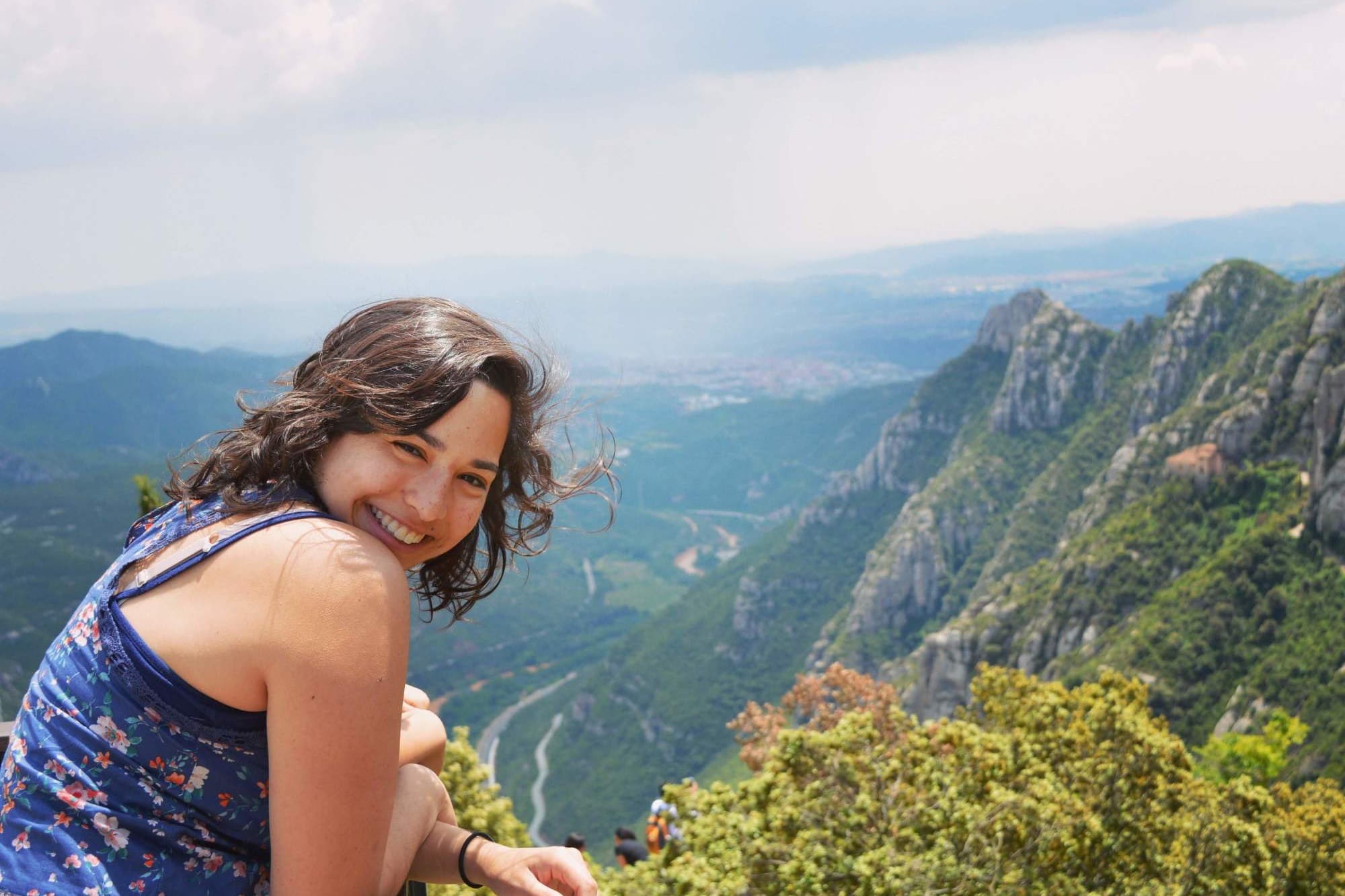 a woman in a blue tank top overlooks a lush valley