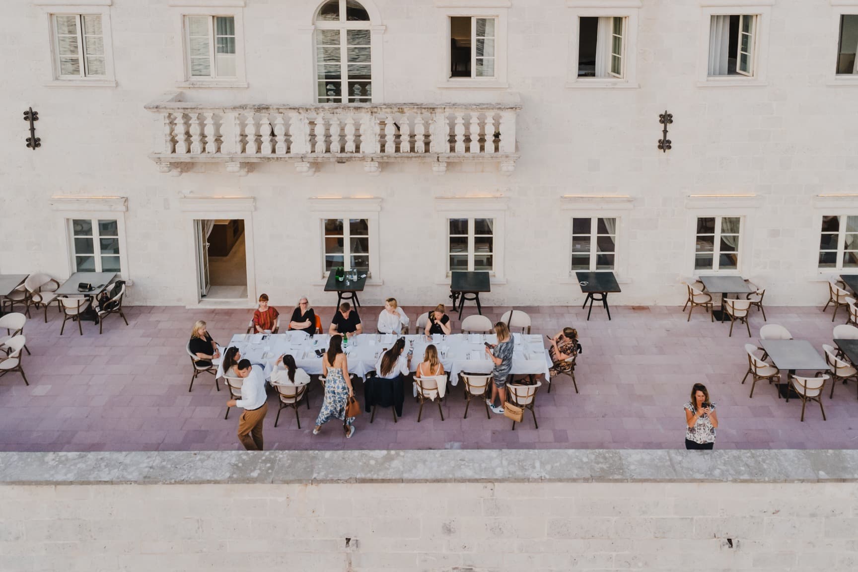 people sit at a sidewalk table in front of a white building