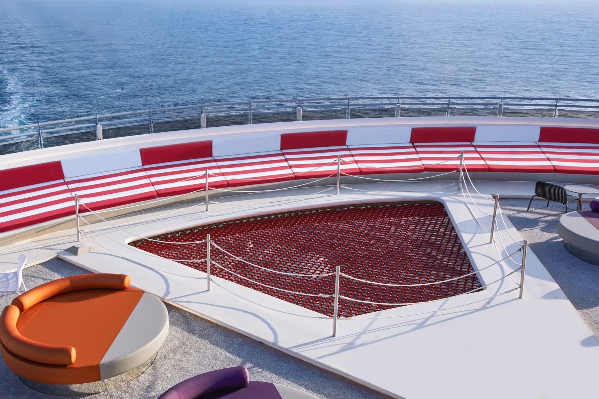 cruise ship deck with a red relaxation net and orange and purple loungers