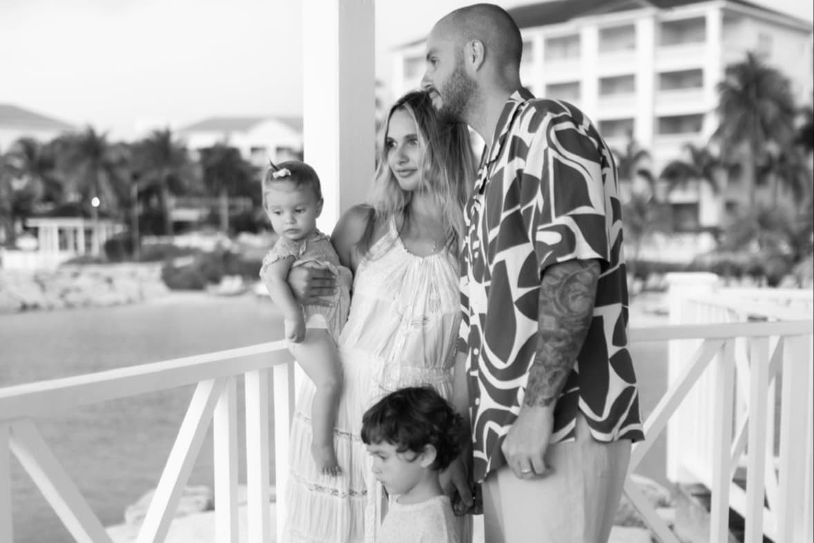 a woman and a man and two children stand on a porch