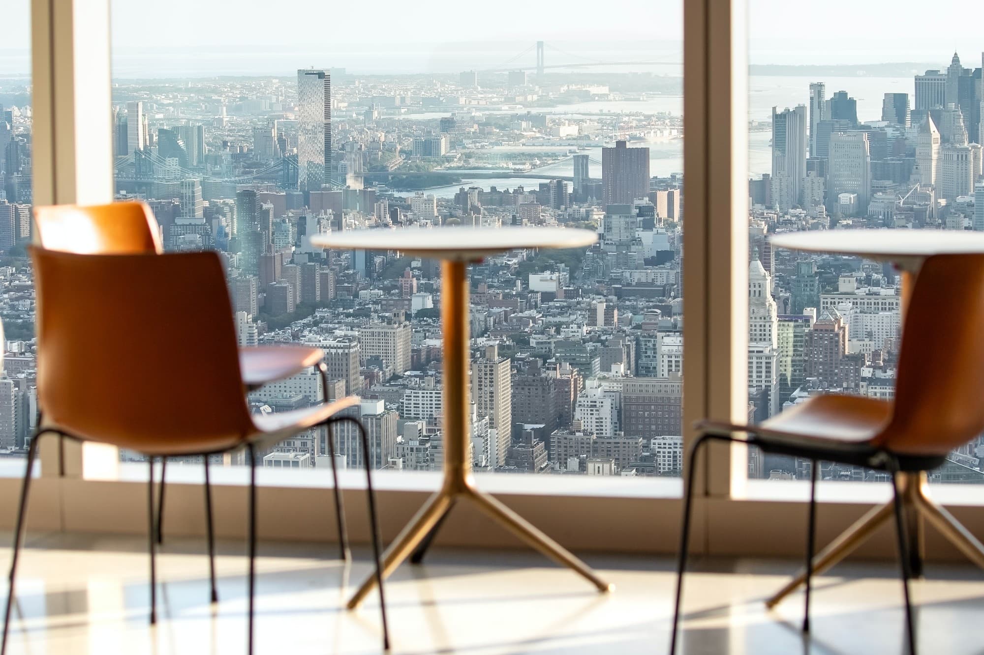 a table and chairs overlooking a city view through floor-to-ceiling windows