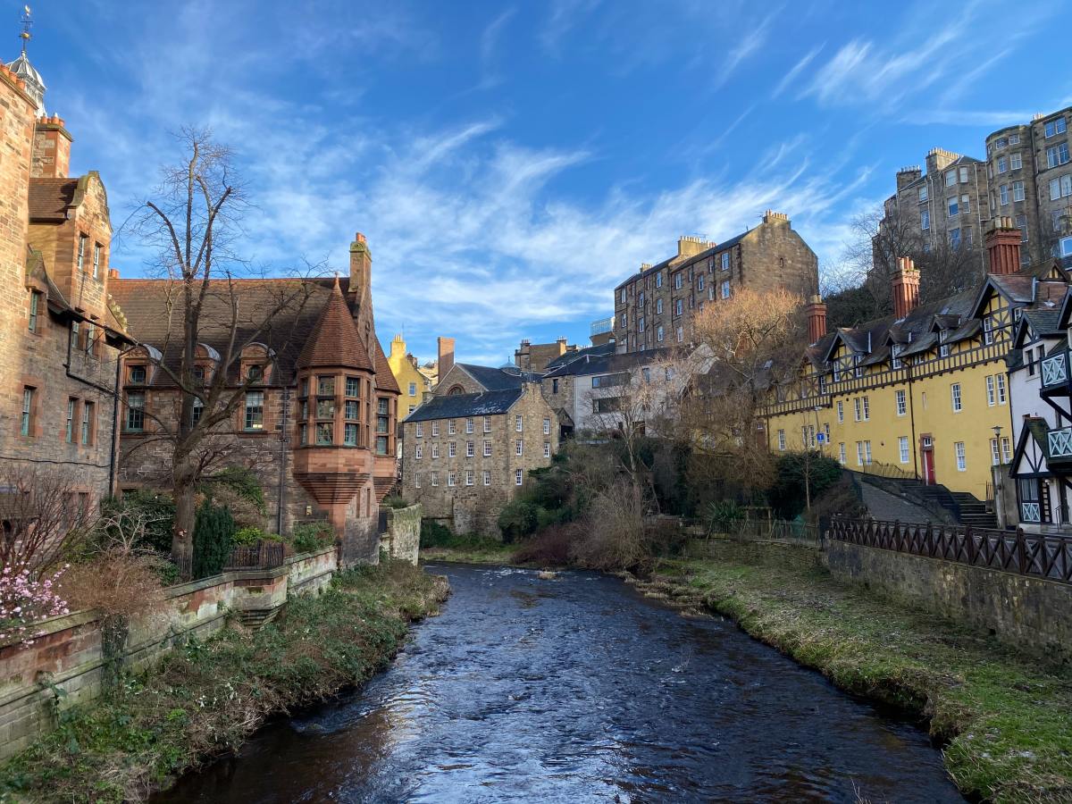 Canal lined with historic buildings in Edinburgh on a shady day.