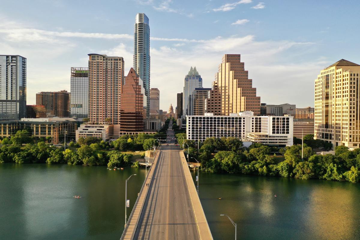 Highway bridge over lake leading to the skyline of new developments in Austin, Texas on a sunny day.