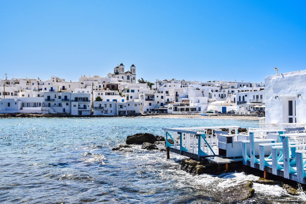 White and blue buildings in front of ocean on clear day in Greece.