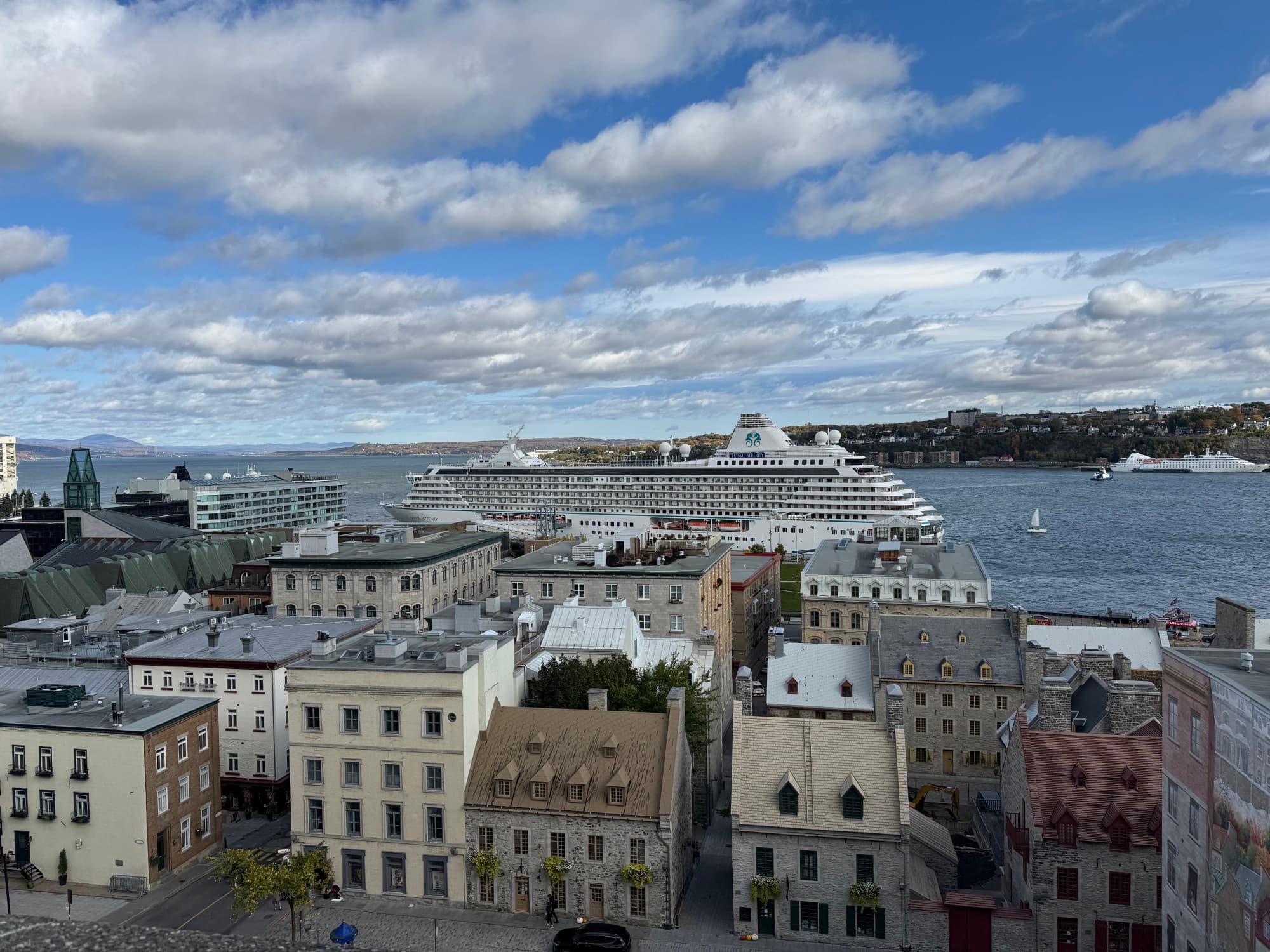 An aerial view of a town with a a cruise ship in the water behind city buildings