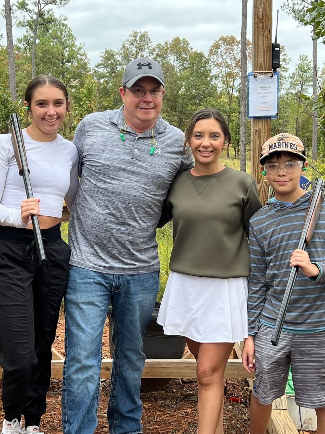 A family posing for a photo together outside with holding firearms