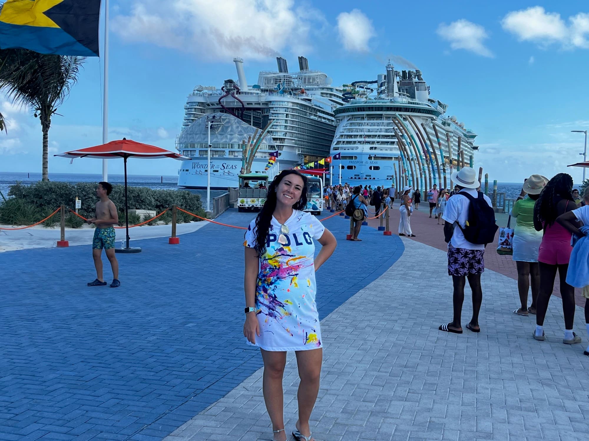 A posing standing and posing for a photograph in front of two large cruise ships