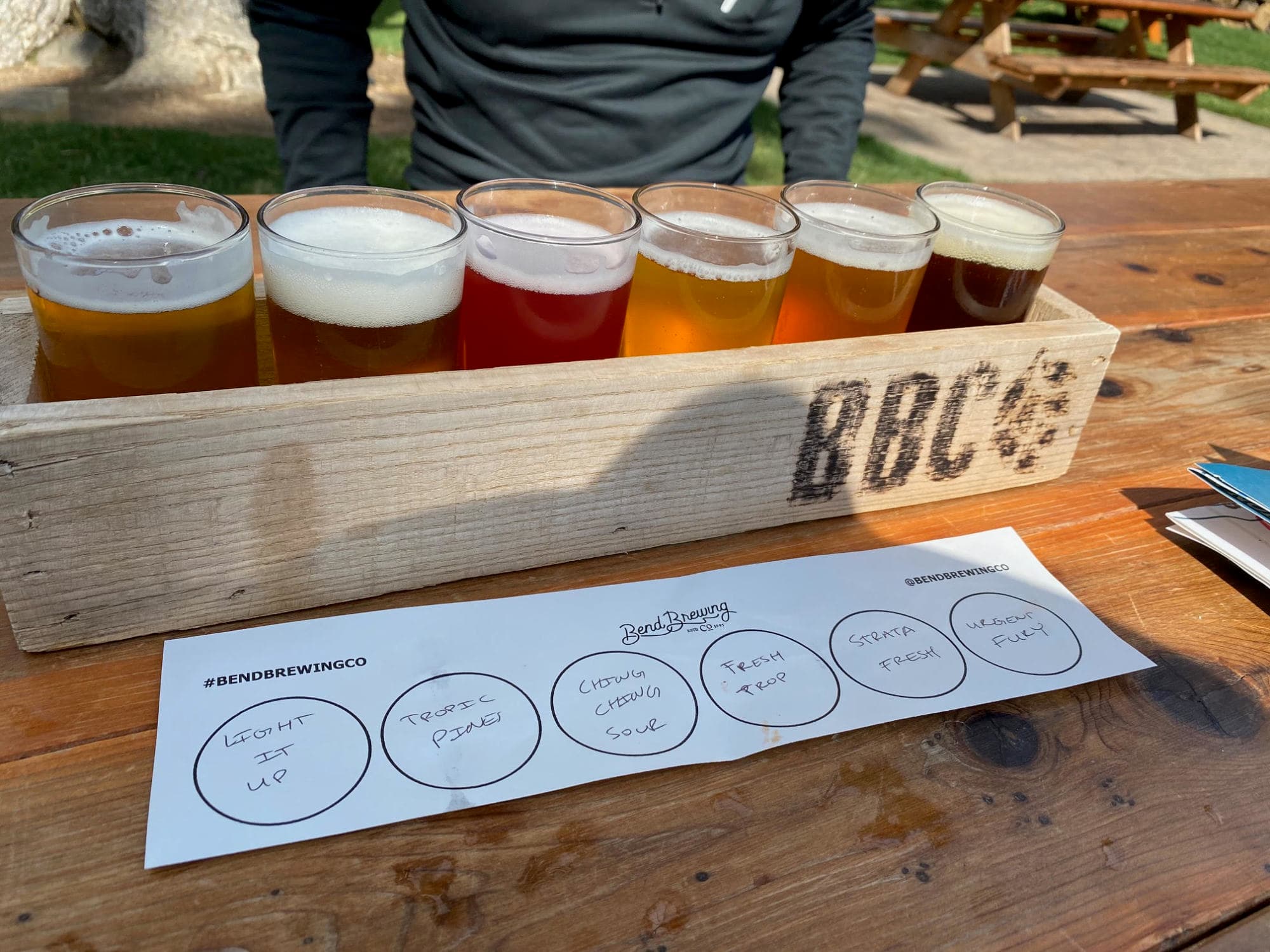 Bend Brewing Company features beer flights on wooden tables in the sunshine.