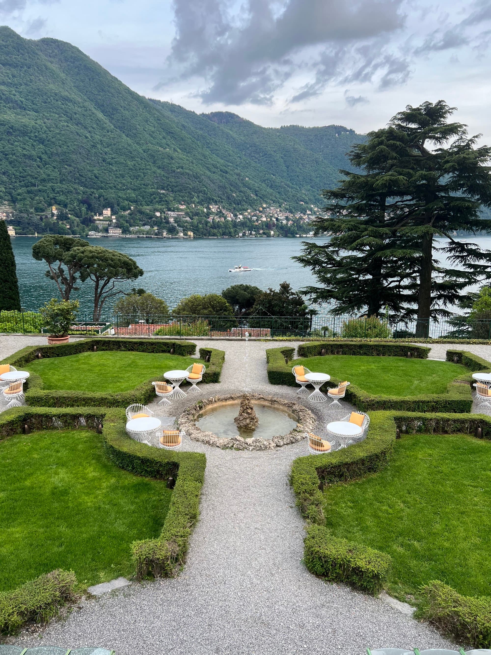 A breathtaking lakeside view with mountains cascading to the horizon on a clear day dotted with clouds.