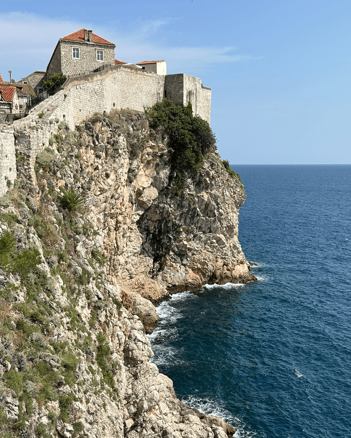 A cliffside next to a body of water with a building on top
