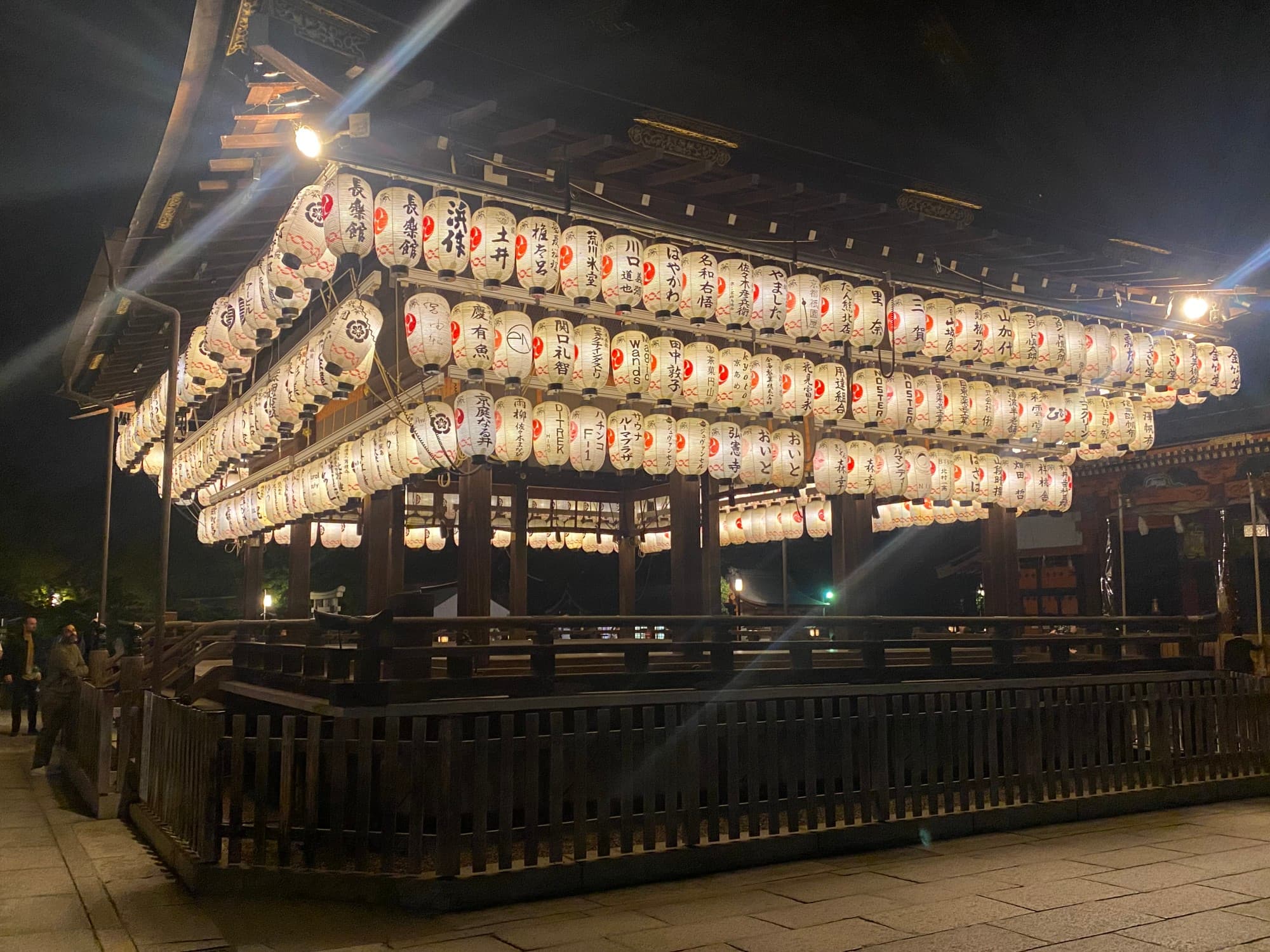 An wooden structure filled with lit lanterns at dark - Yasaka Shrine