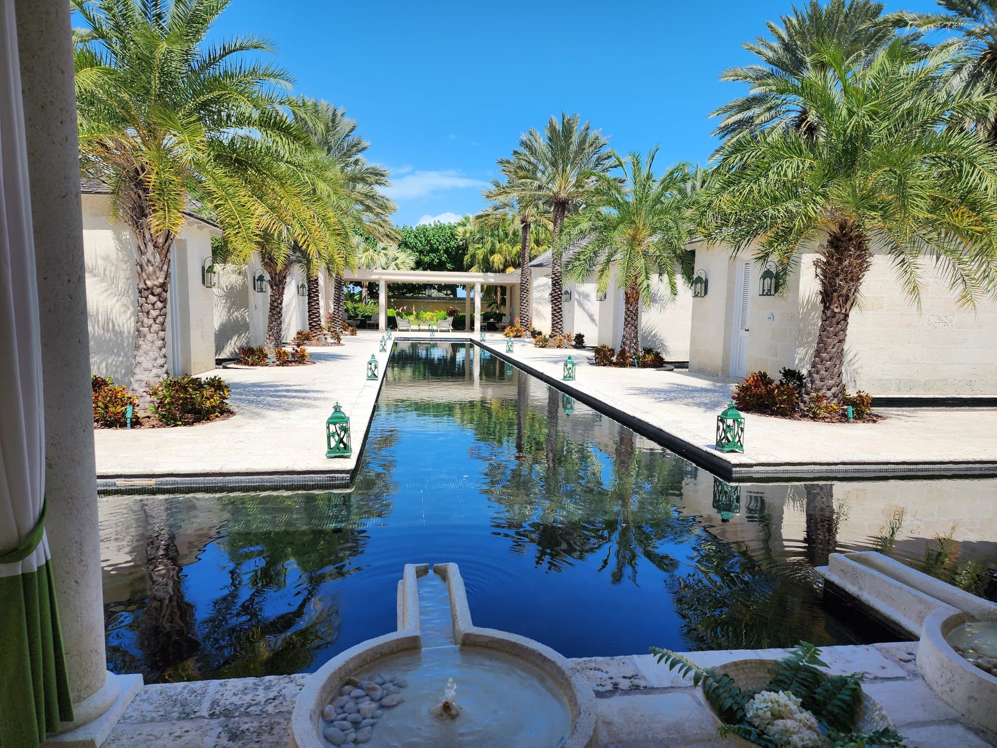 A view from the spa at The Palms overlooking a reflecting pool surrounded by palm trees under a clear sky.