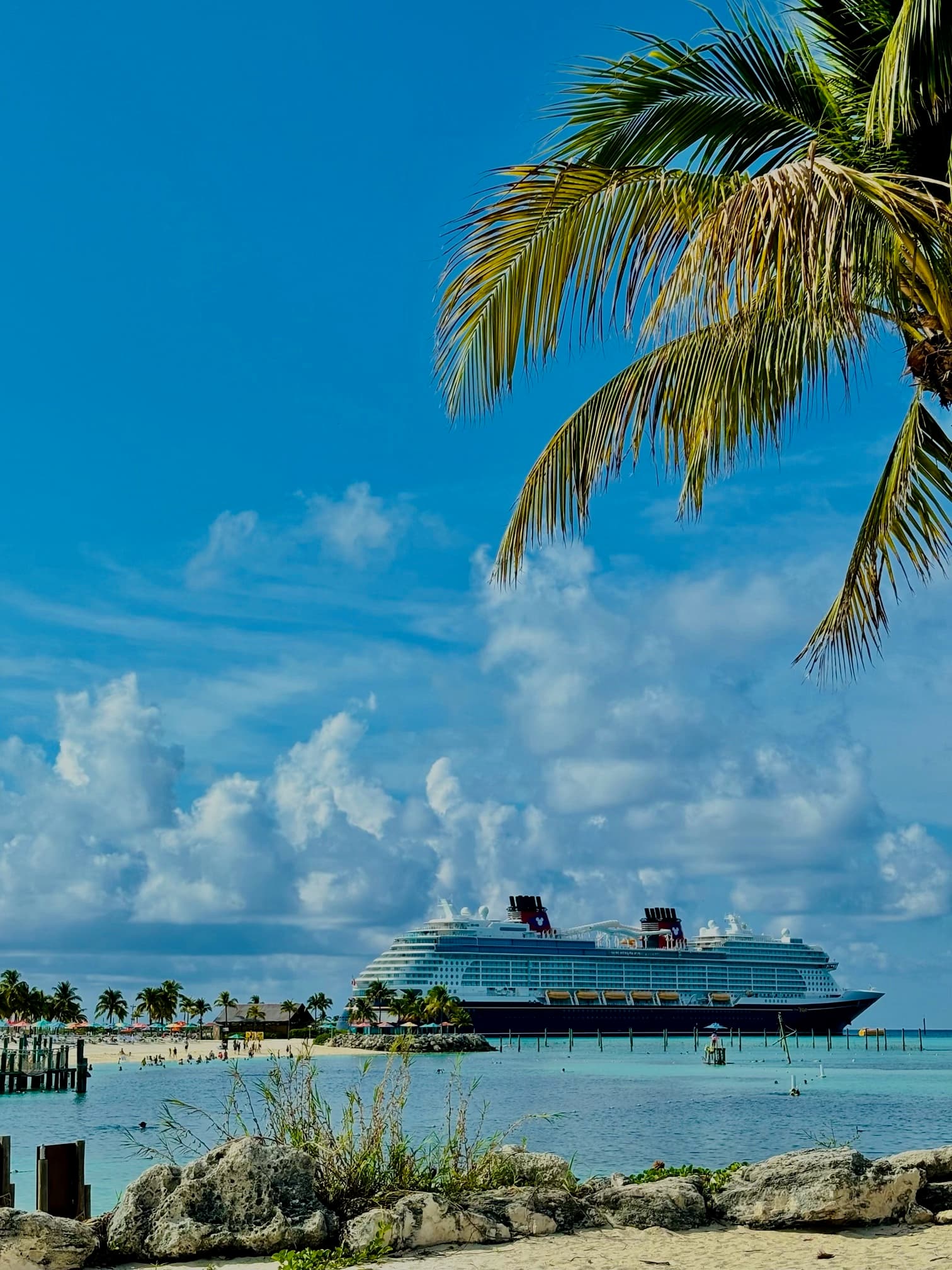 A view from the dock of a large luxury cruise ship on a calm ocean on a clear blue day.