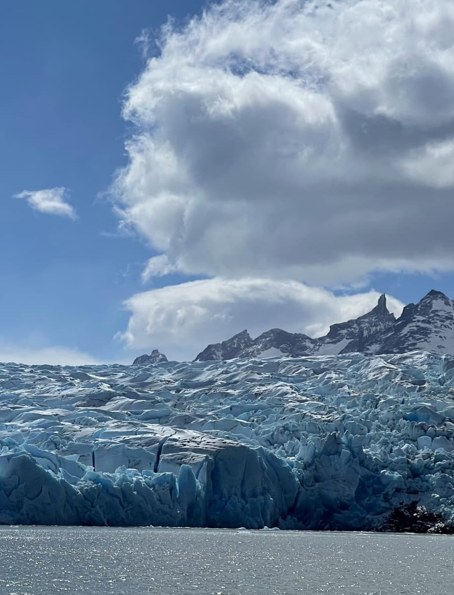 A glacier with a sunny sky and clouds.