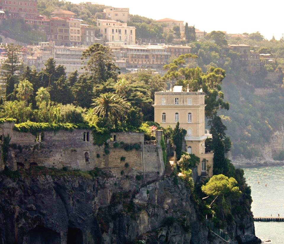 A building on the cliffside with a view of other buildings in the distance