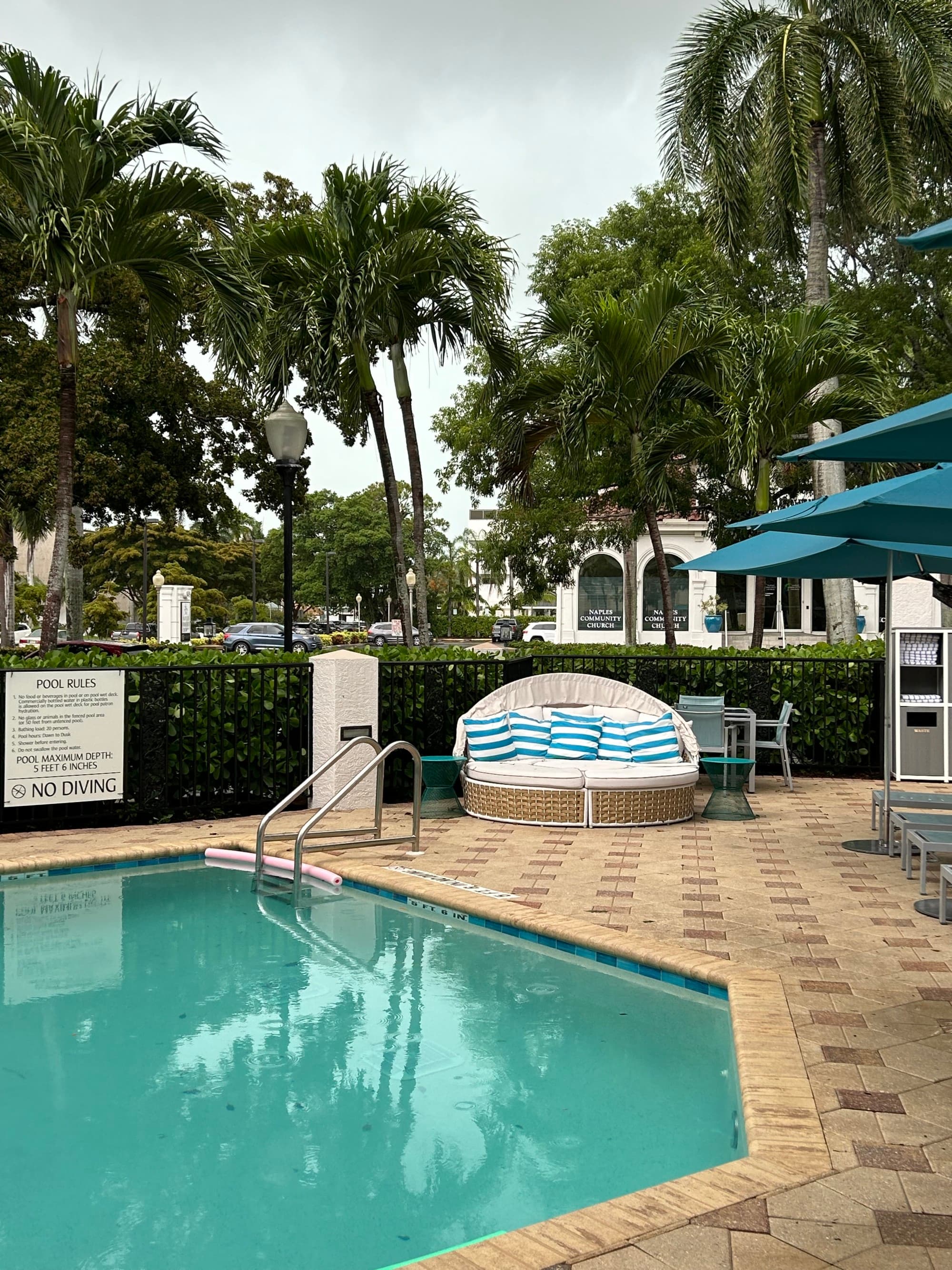 Pool with tiled patio and nearby blue umbrellas.