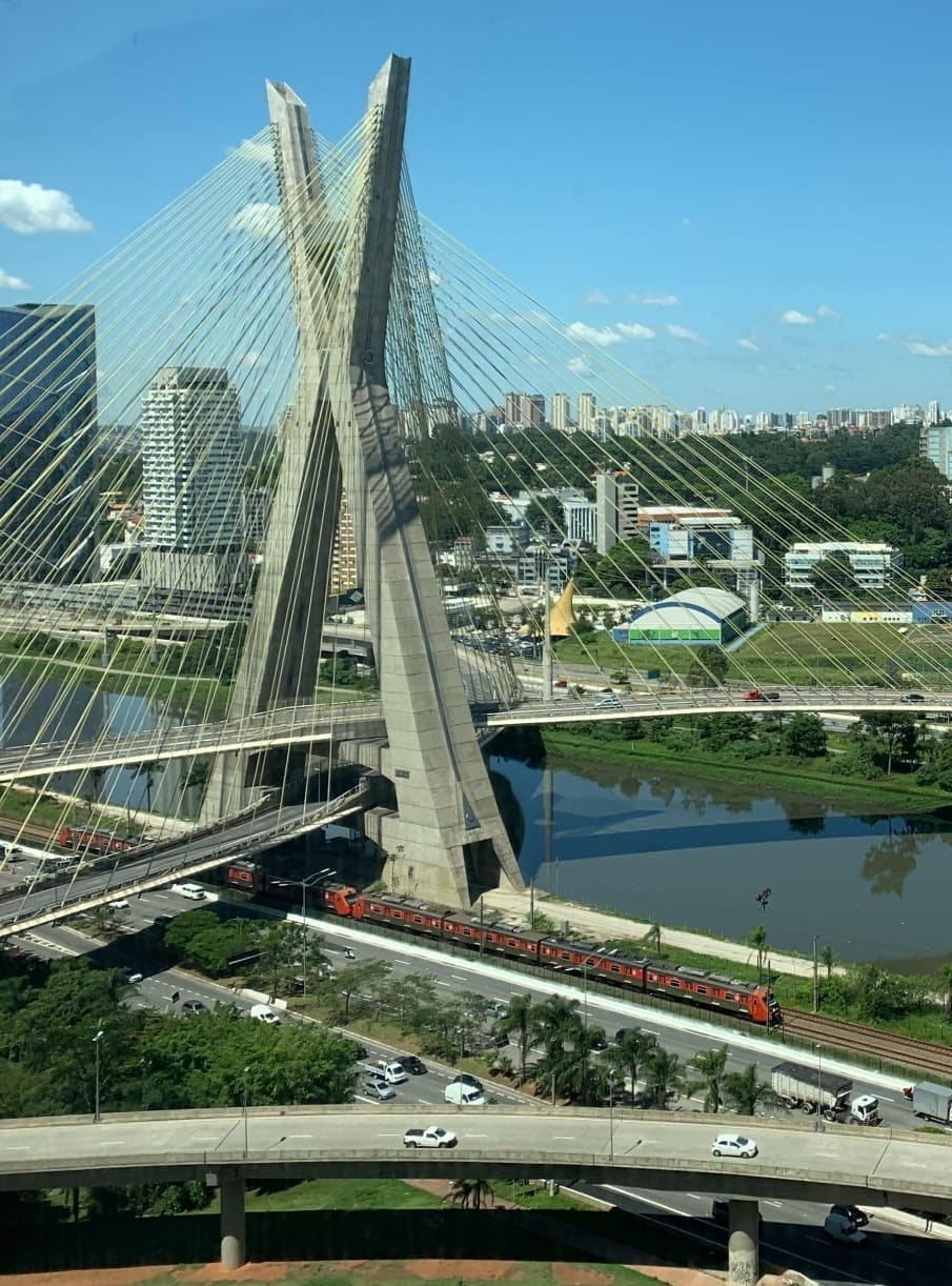 Bridge over a river with a city skyline behind.