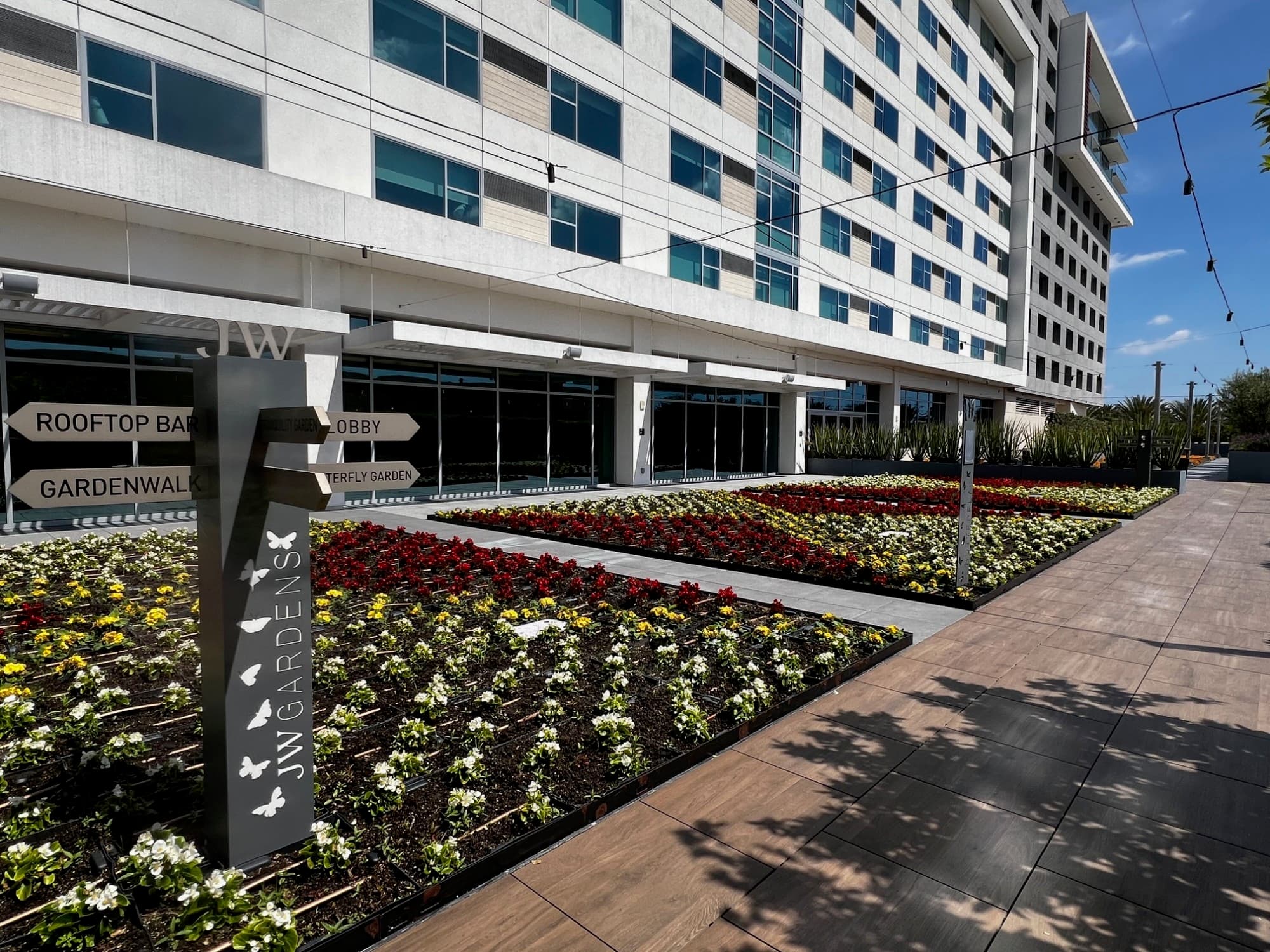 This image depicts a hotel exterior with windows, doors, signage, a sidewalk and landscaping in view.