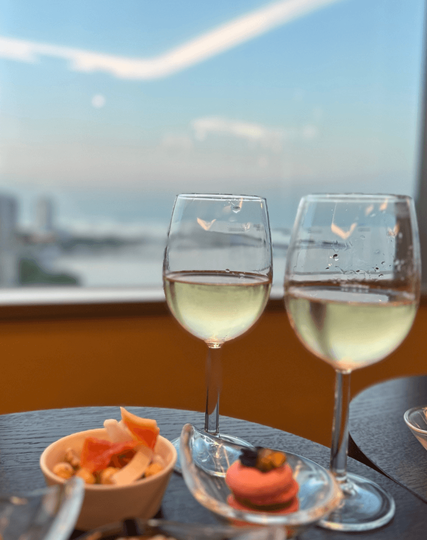Two wine glasses holding white wine sitting in a table