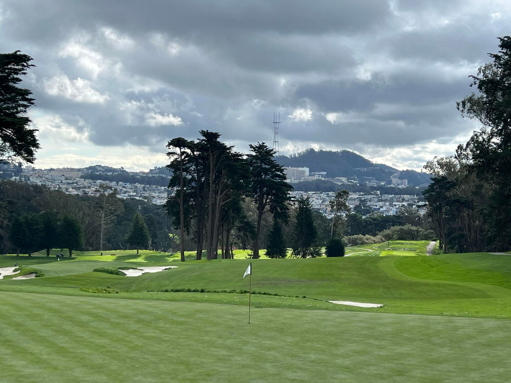A view of a hole on a golf course with a city view in the background.