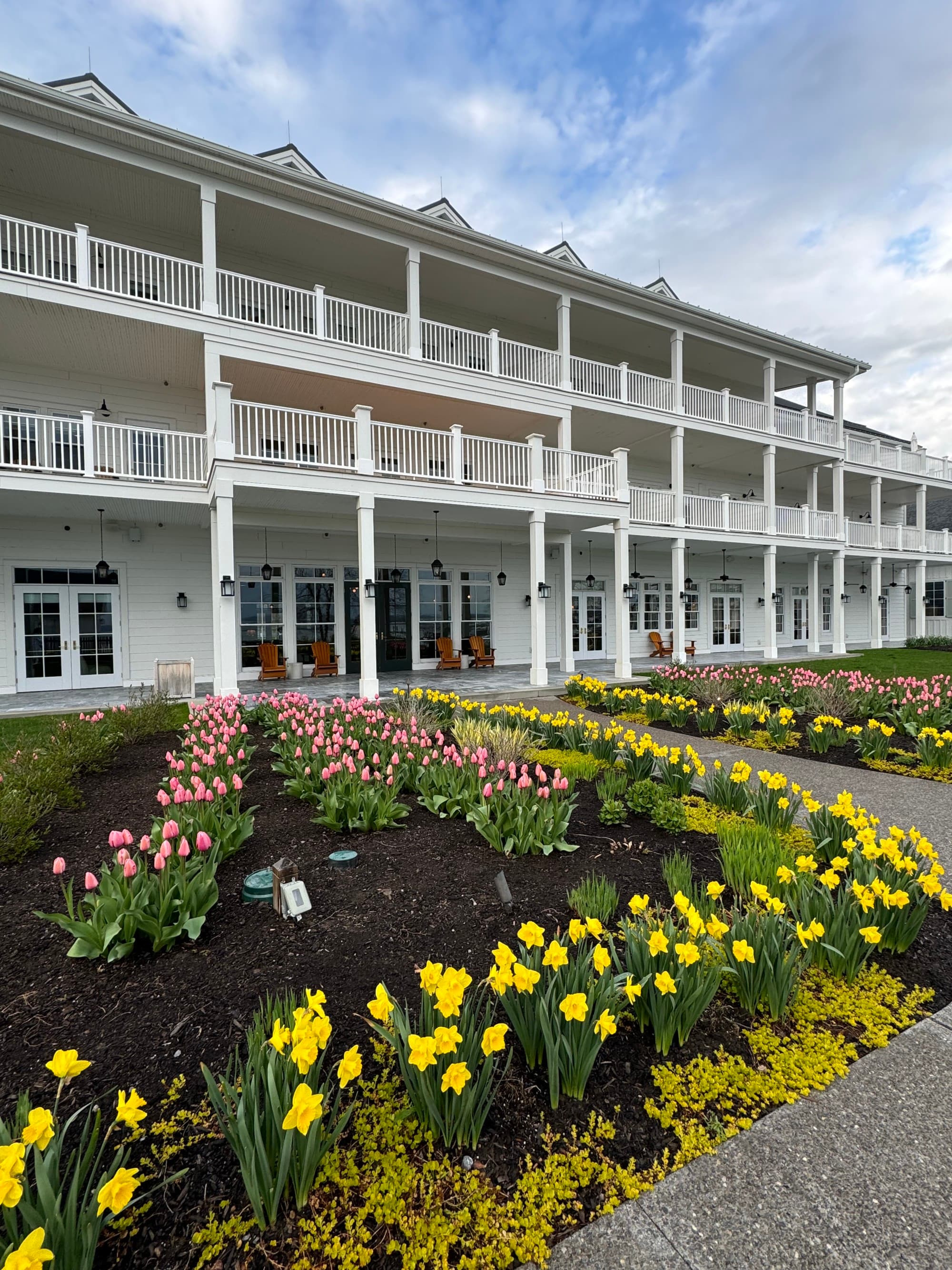 The exterior of the lake house, a white building with balconies and flowers out front - Noelle Rudloff
