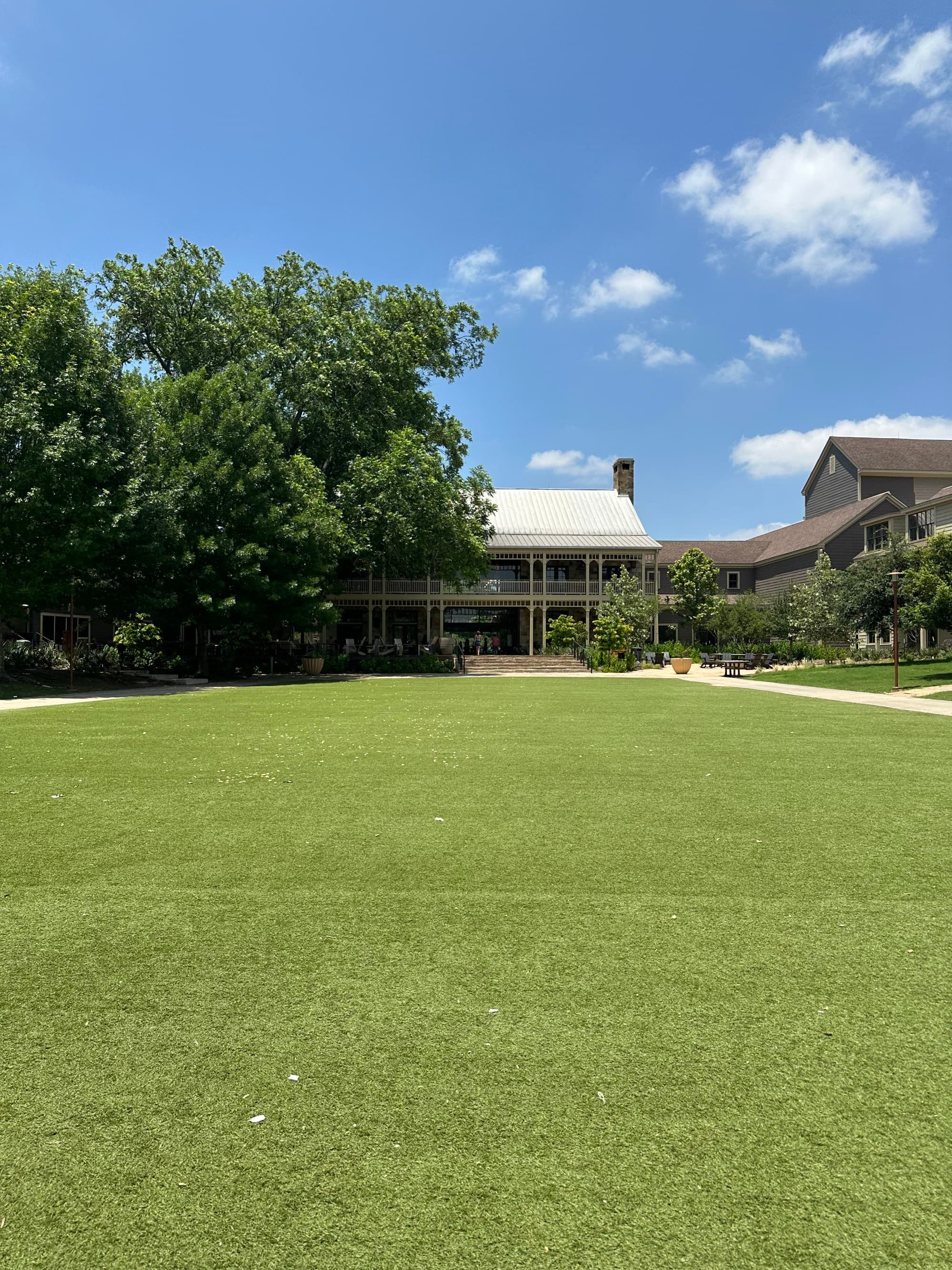 A green lawn in front of a house under a blue sky