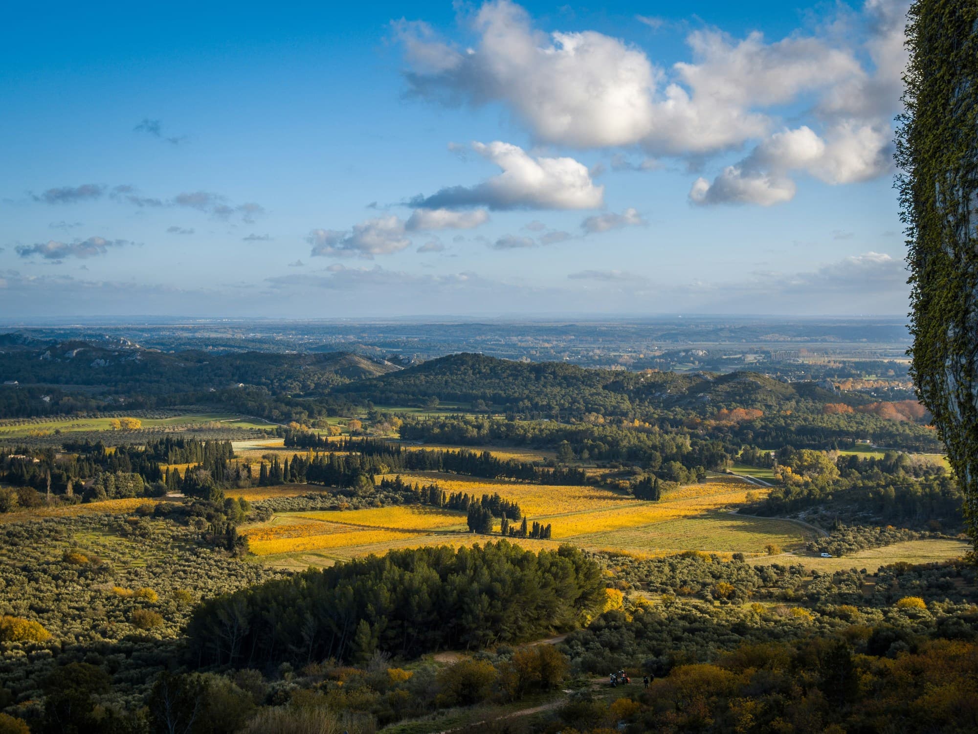 Les Baux de Provence, France on a sunny day with fields in the distance and light clouds.