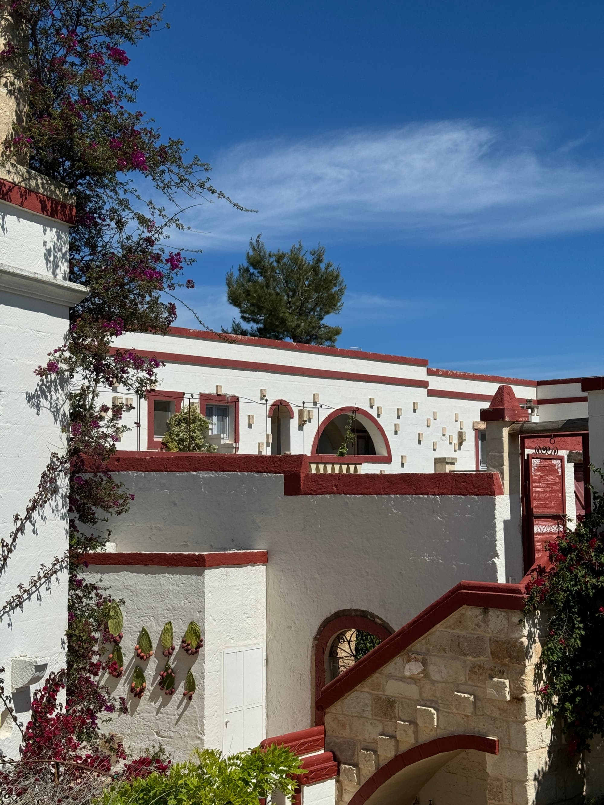 A view of a white stucco and charming villa on a sunny day in Masseria, Italy.