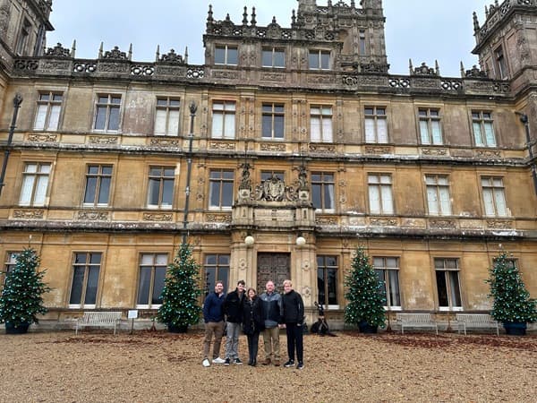 A group photo before the Highclere Castle in England, on a mildly foggy day.
