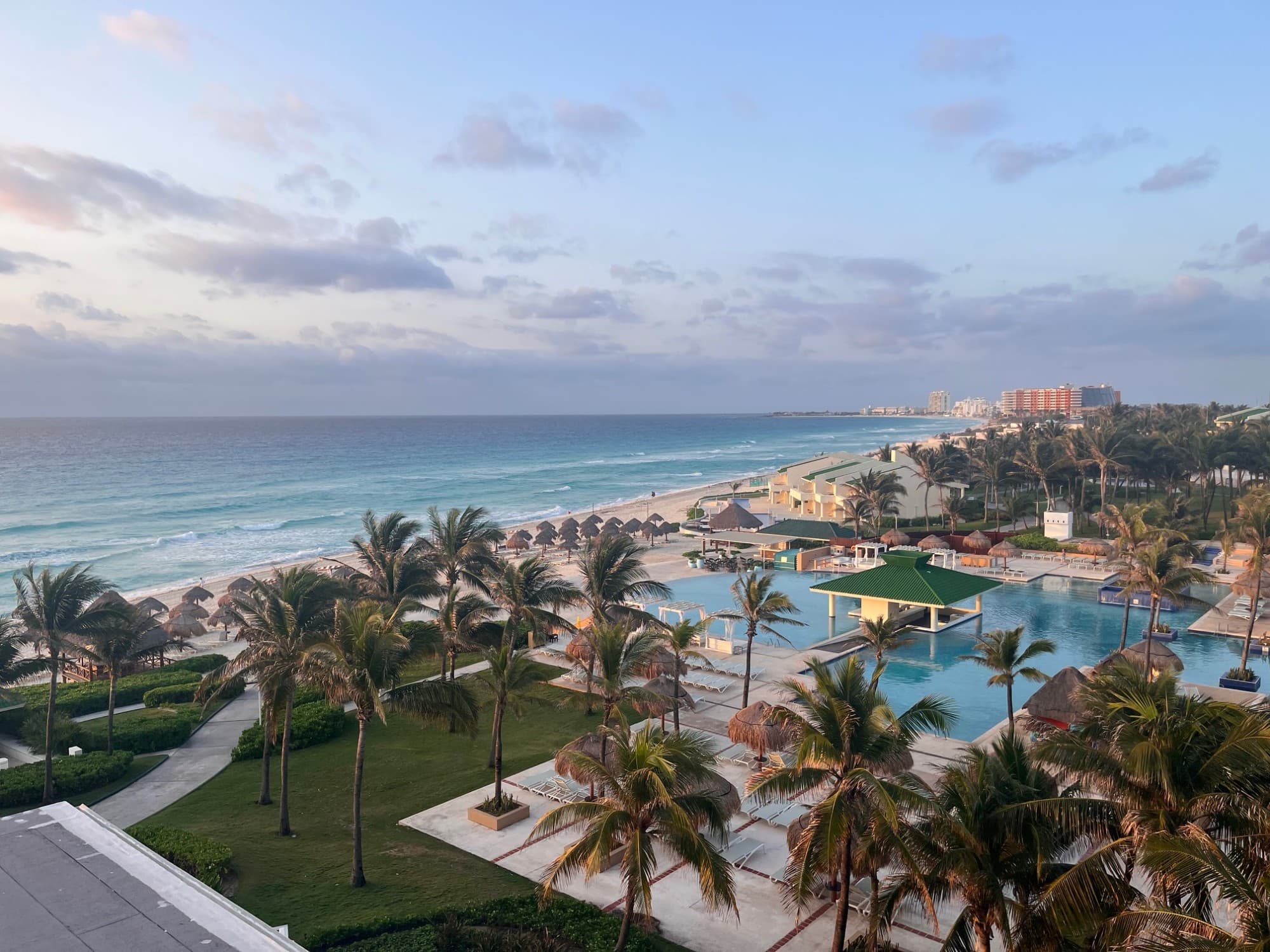 A view of the hotel grounds and beach under a semi-clouded sky.