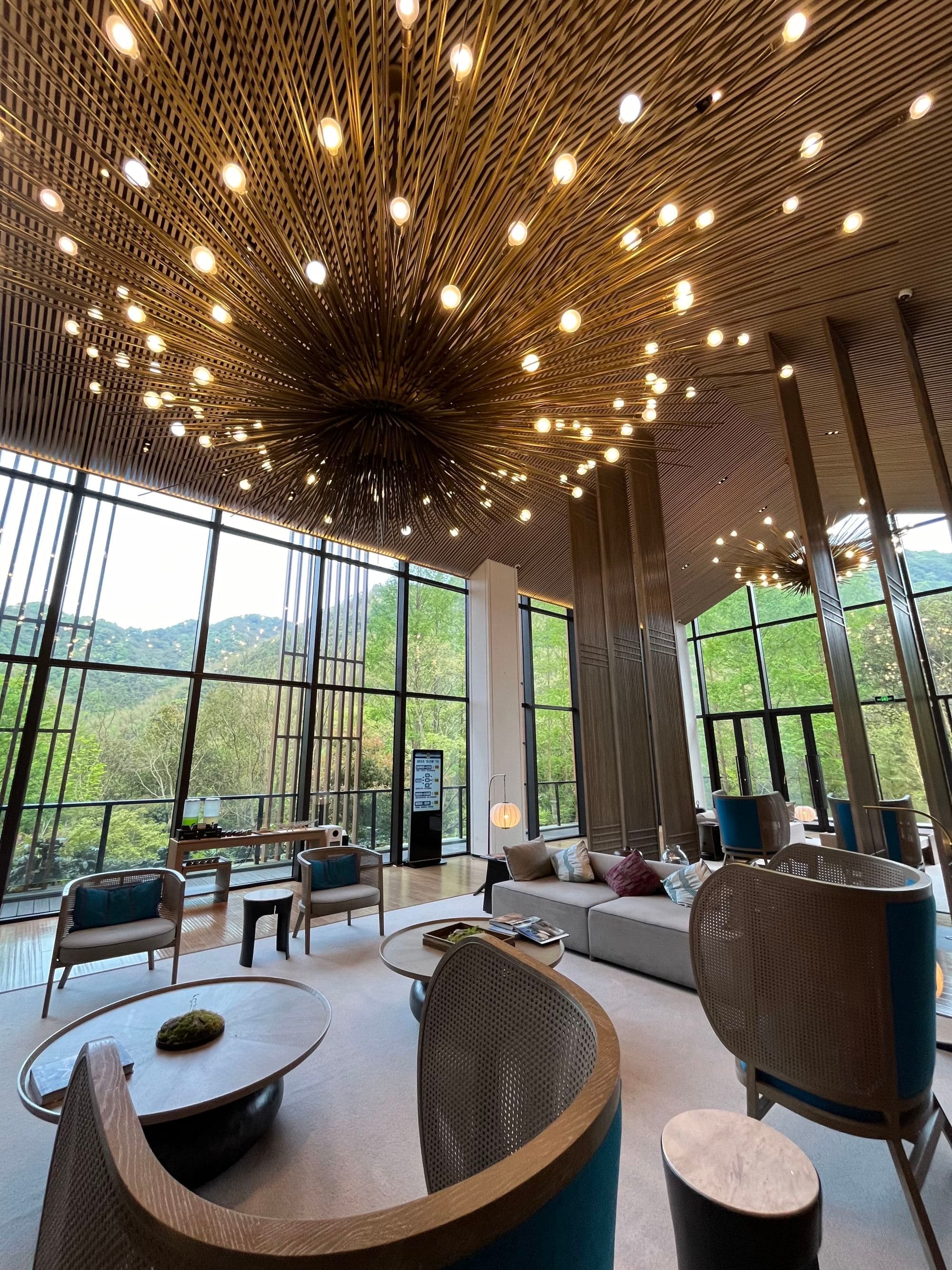 A lobby of a hotel with various seating a large, abstract lighting feature
