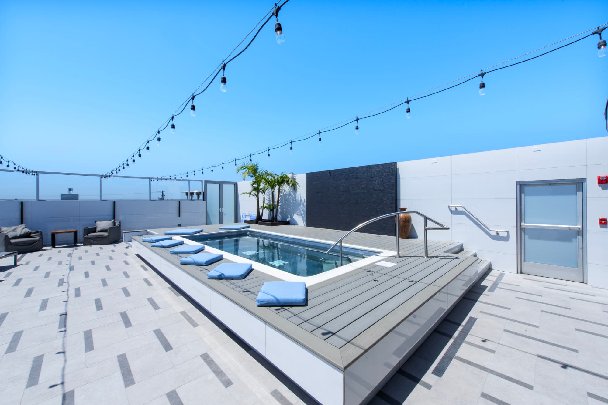 A hotel's rooftop pool, under a clear, blue sky.