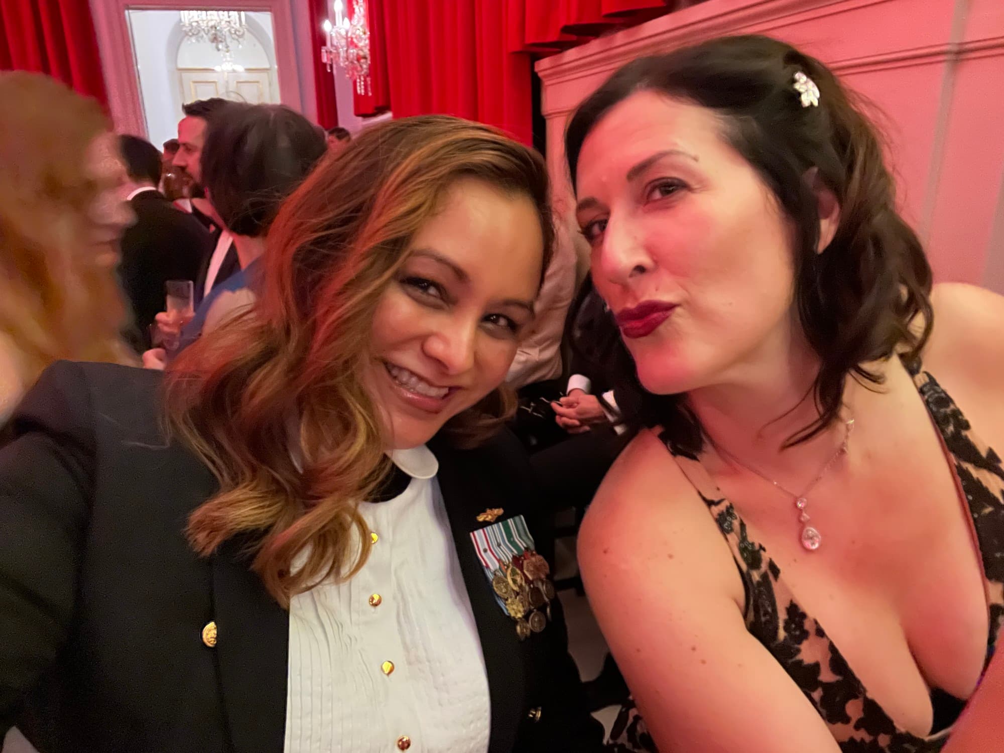 April in a military officer's outfit taking a selfie with a woman in a dress at the ball