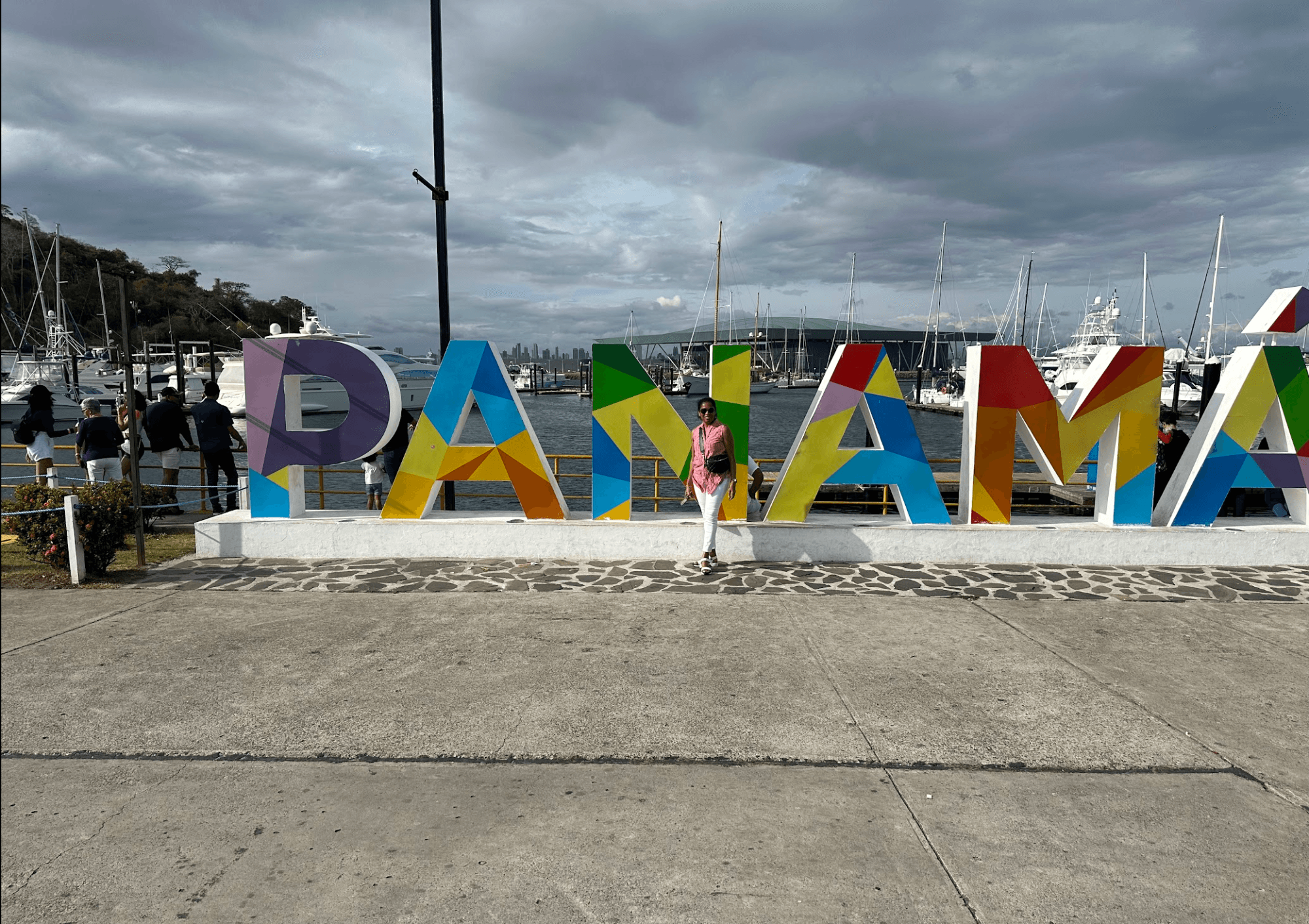 A view of a sign that says Panama in multi-colored paint. There is a cement sidewalk in front of it and a cloudy grey sky up above.