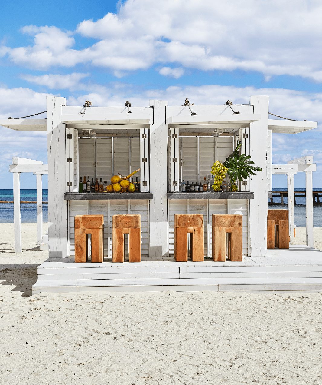 A white beach shack with wooden stools, a bar, citrus and roof coverings in the Riviera Maya, Quintana Roo, Mexico