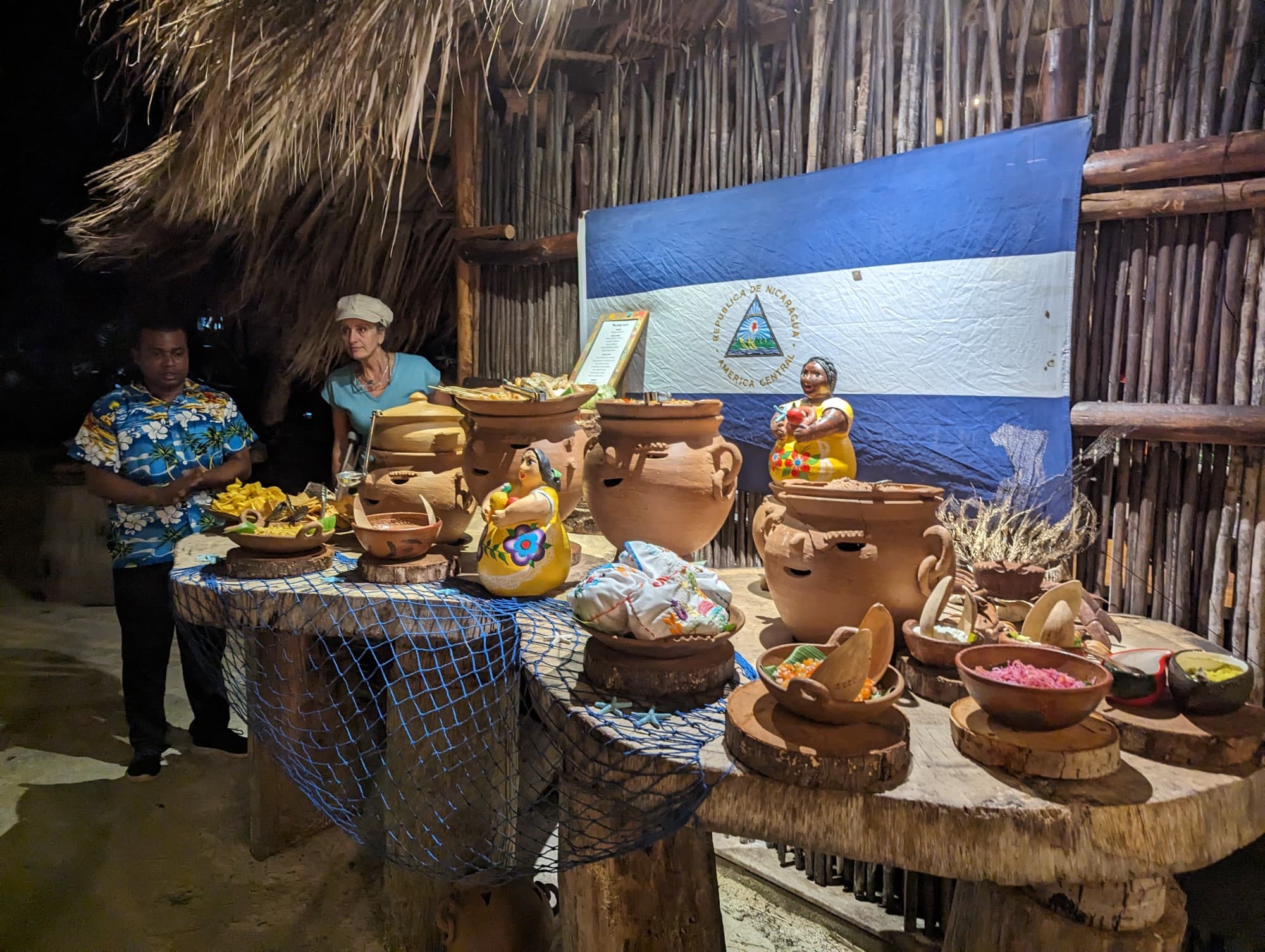 A picture of various ceramics displayed on a table in front of a flag and wooden hut.