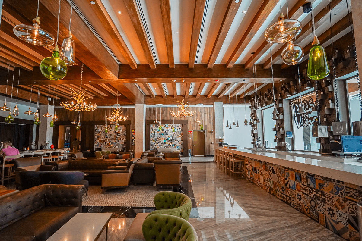 A beautiful hotel interior with paneled ceilings, glass lighting hanging from the ceiling, colorful furniture and a colorfully painted check-in desk.