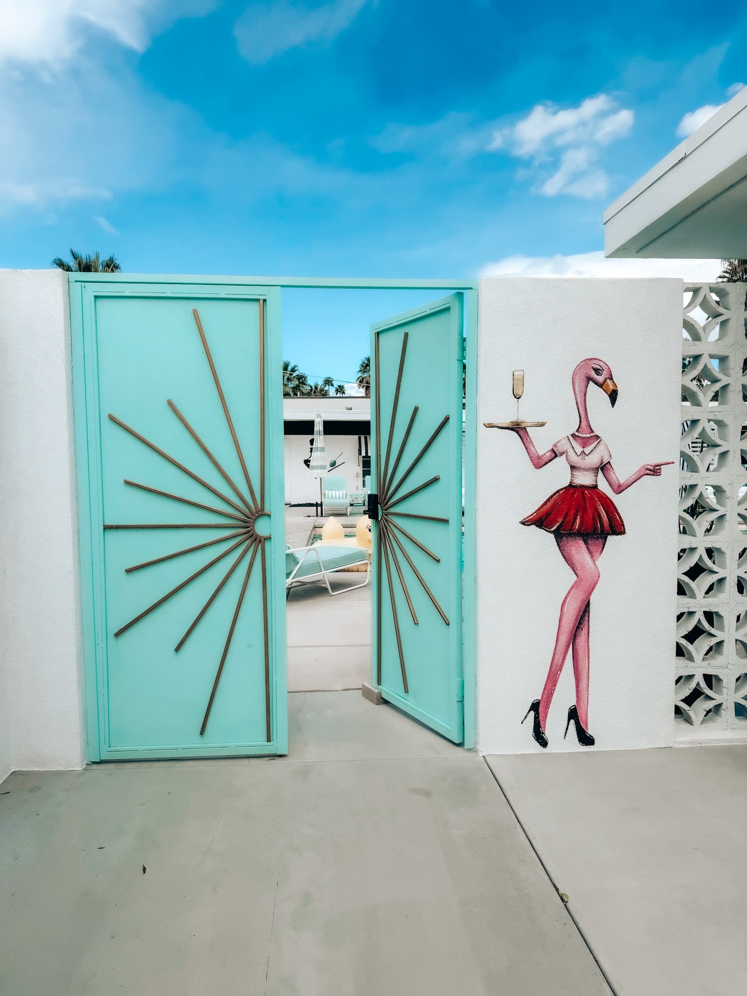 A teal outside door leading to a pool area during the daytime
