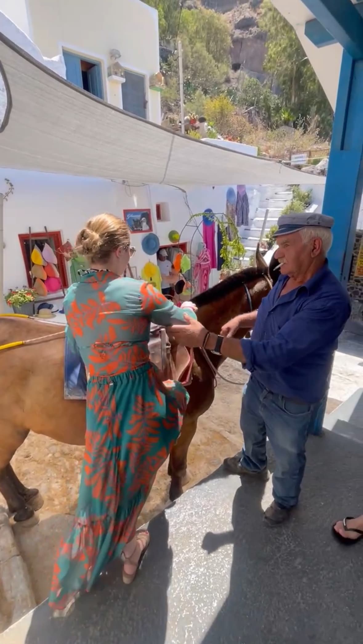 Travel advisor Elaine mounting a donkey with the help of a man in a Greek street