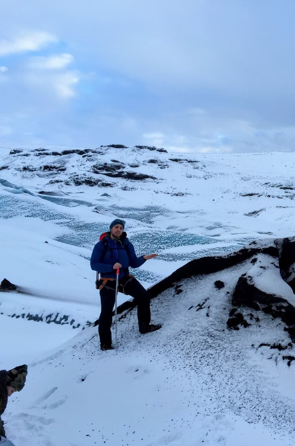 A person posing on a snowy hill surrounded by rocky and snowy terrain.
