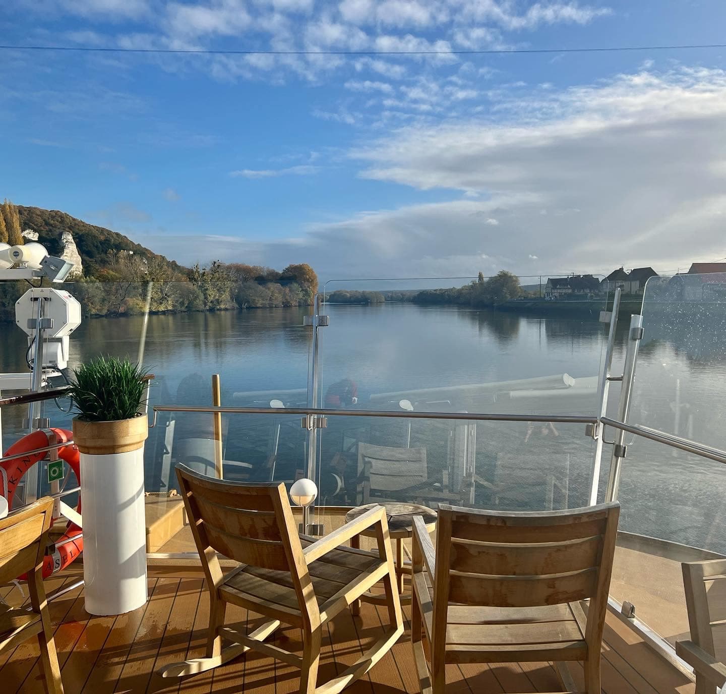 View of the Seine River from a boat with a wood deck and wood chairs - Melissa Curtin